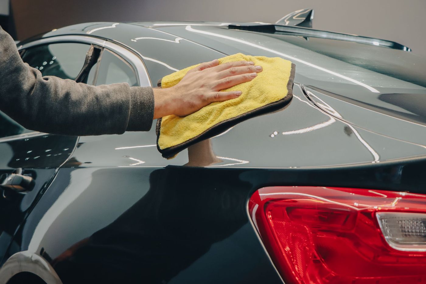 A detailer wiping down a car body panel with a microfibre cloth. Stock photograph, not Uriel Detailing.