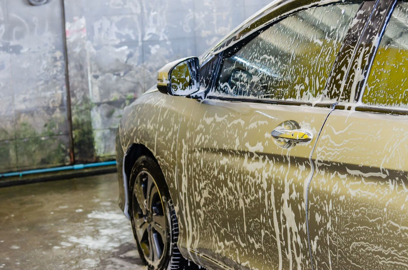 A car covered in white foam during a hand wash. Stock photograph.