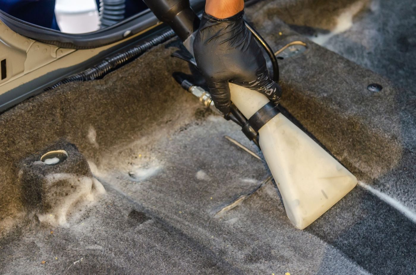 A detailer vacuuming a dirty car carpet. Stock photograph.