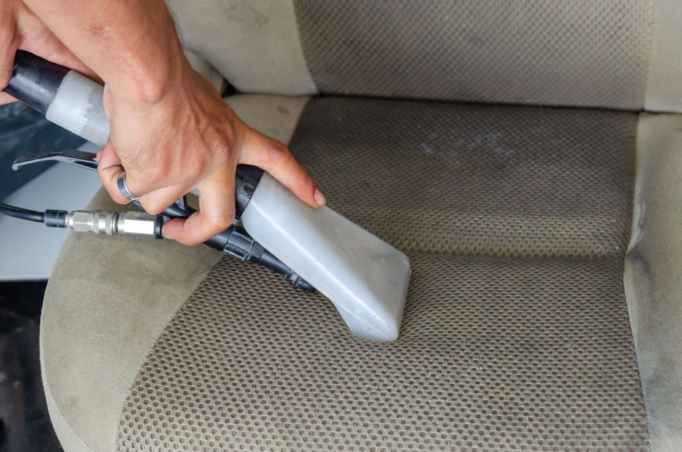 A car seat being cleaned with a hot water extraction tool. Stock photograph.